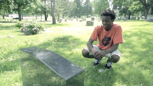 Photo of boy in front of gravestone